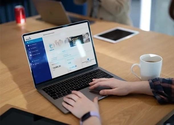 A laptop displaying the Elavon Connect portal on screen, placed on a wooden desk with a blurred background.